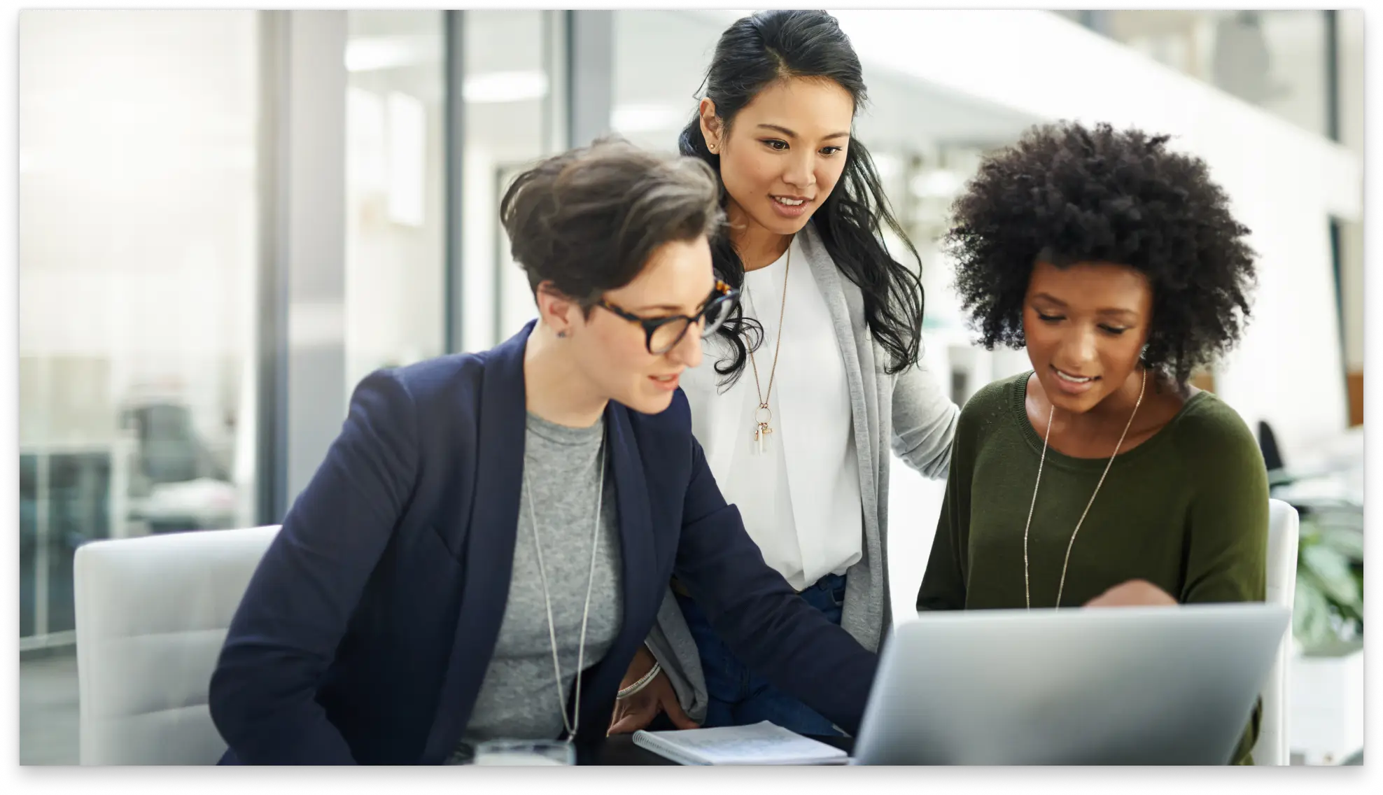 Three people collaborating while reviewing financial data on a laptop