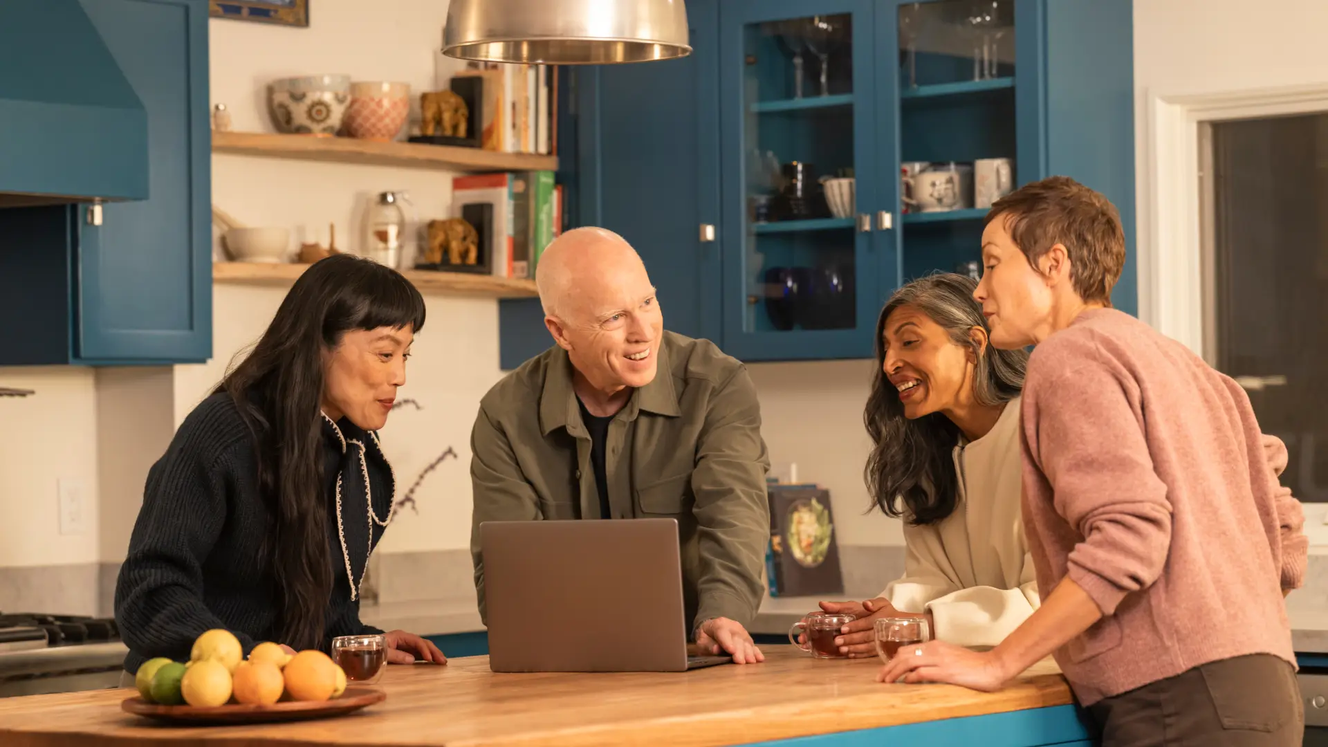 Family members gathered around a table looking at a laptop.