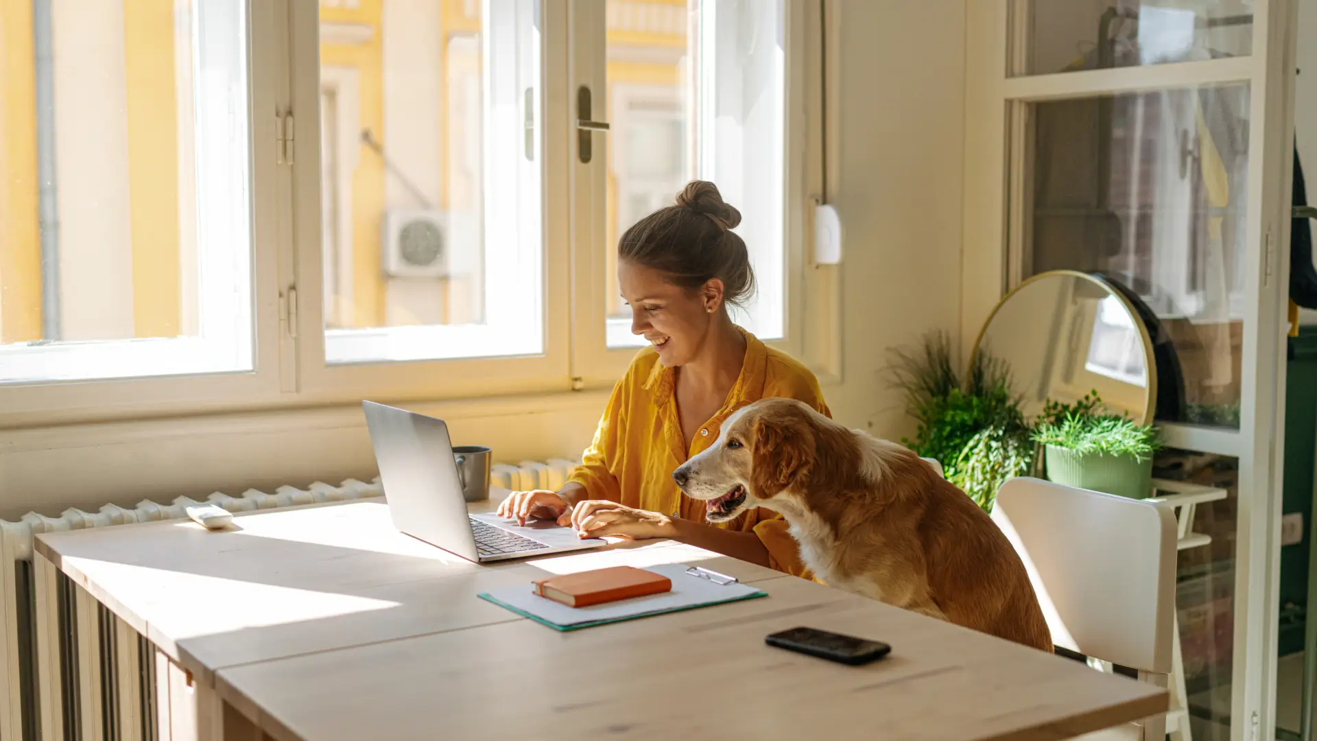 Person working on a laptop at home with a dog nearby.