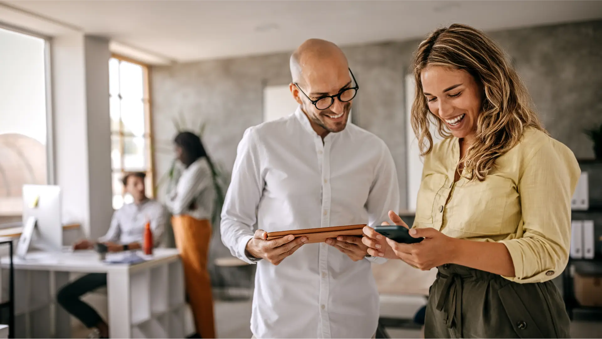 Two people working in an office looking at a mobile device