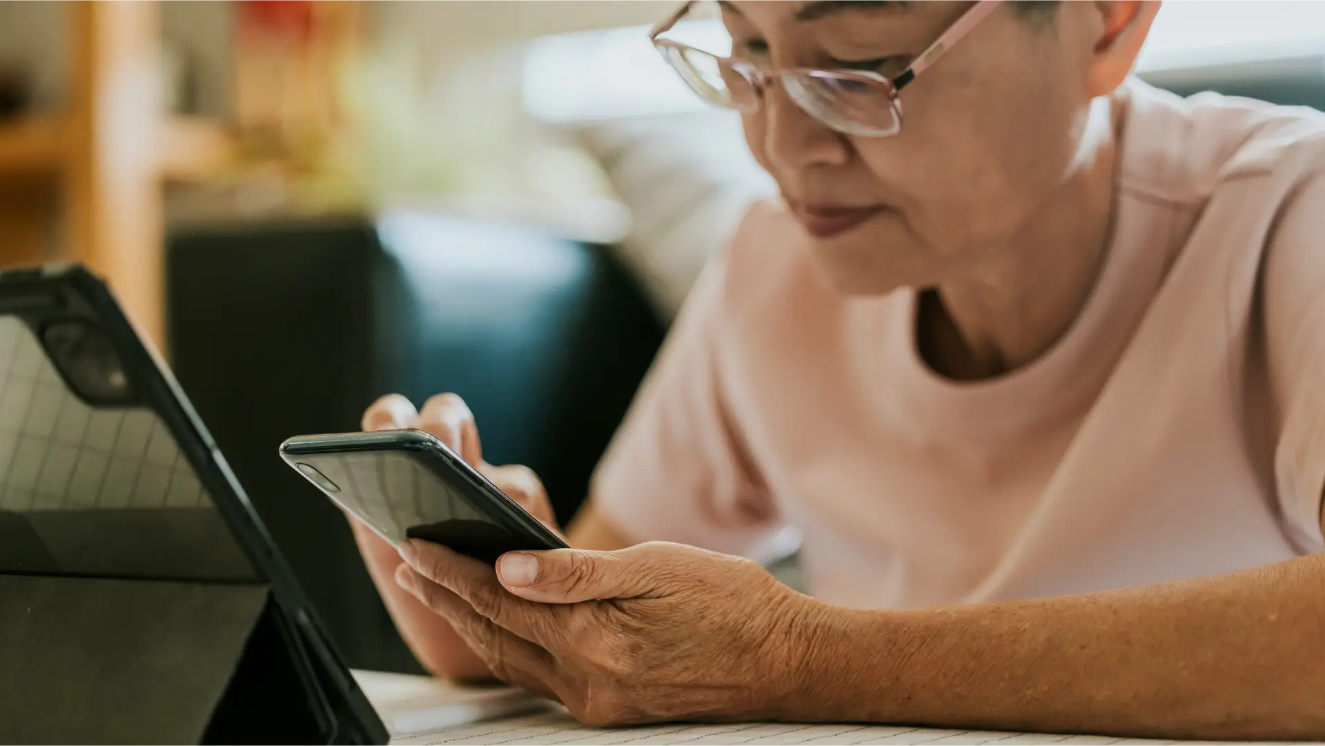 A close up of a woman on her phone with a laptop at a desk