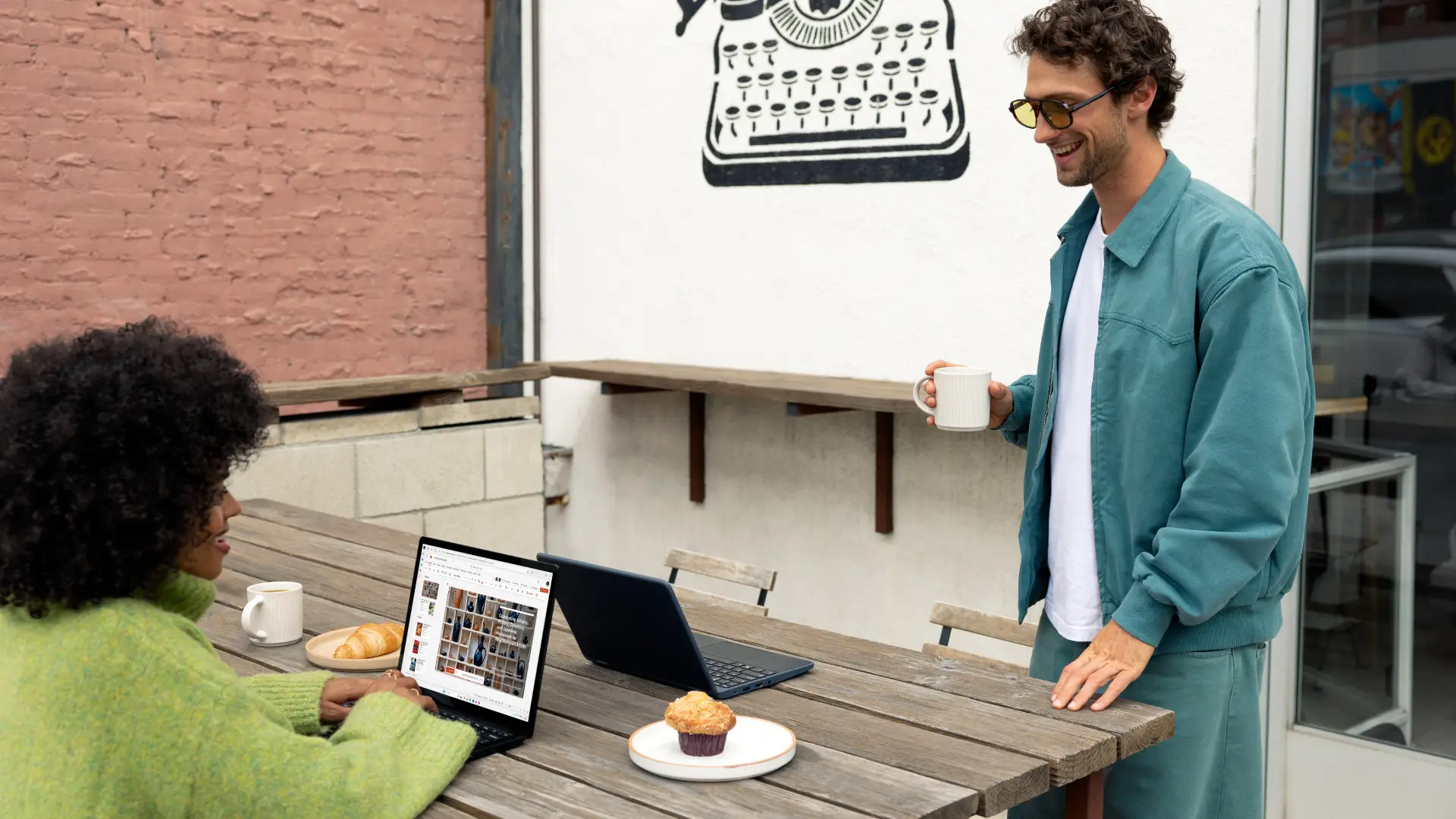 Two people working at a cafe on laptops