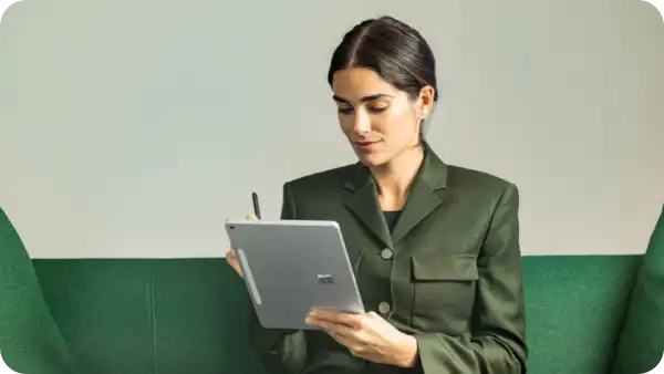 A woman in a green suit using a tablet device